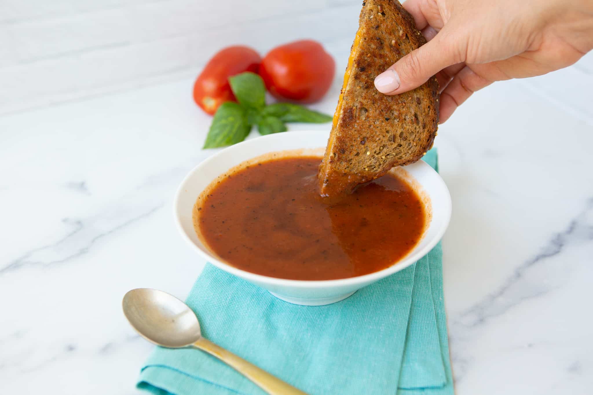 Dipping grilled cheese into a bowl of tomato soup