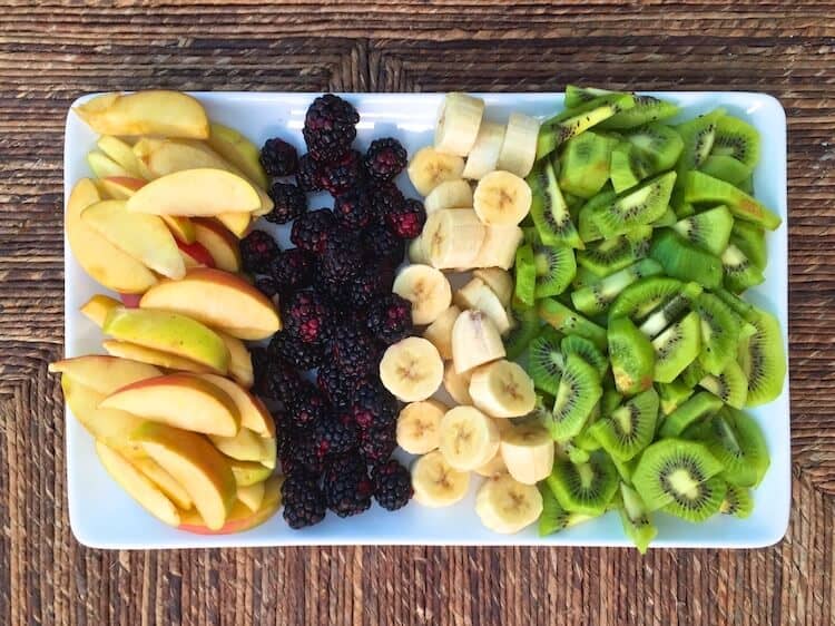 sliced fruit including apples, black berries, bananas, and kiwi