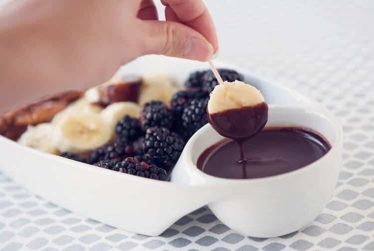 dipping fresh fruit into Vegan Chocolate Fondue