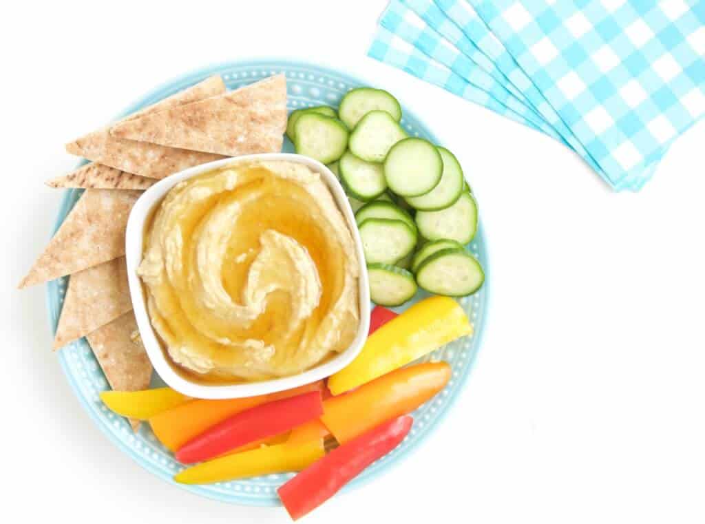 hummus on a plate with pita and veggies