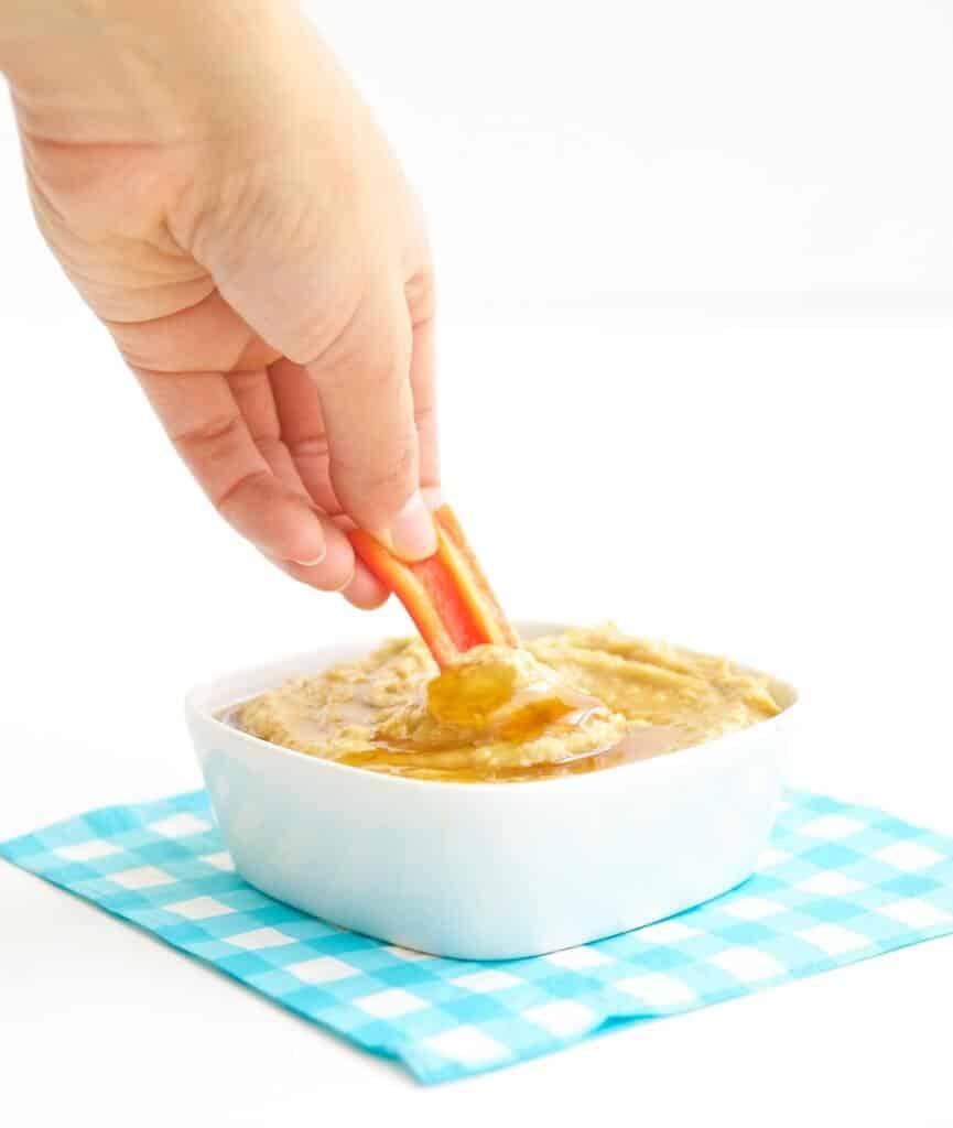 dipping bell pepper into hummus