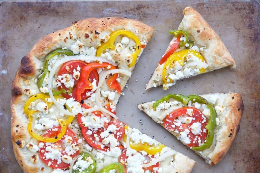 Grilled Veggie Pizza sliced topped with goat cheese and fresh vegetables