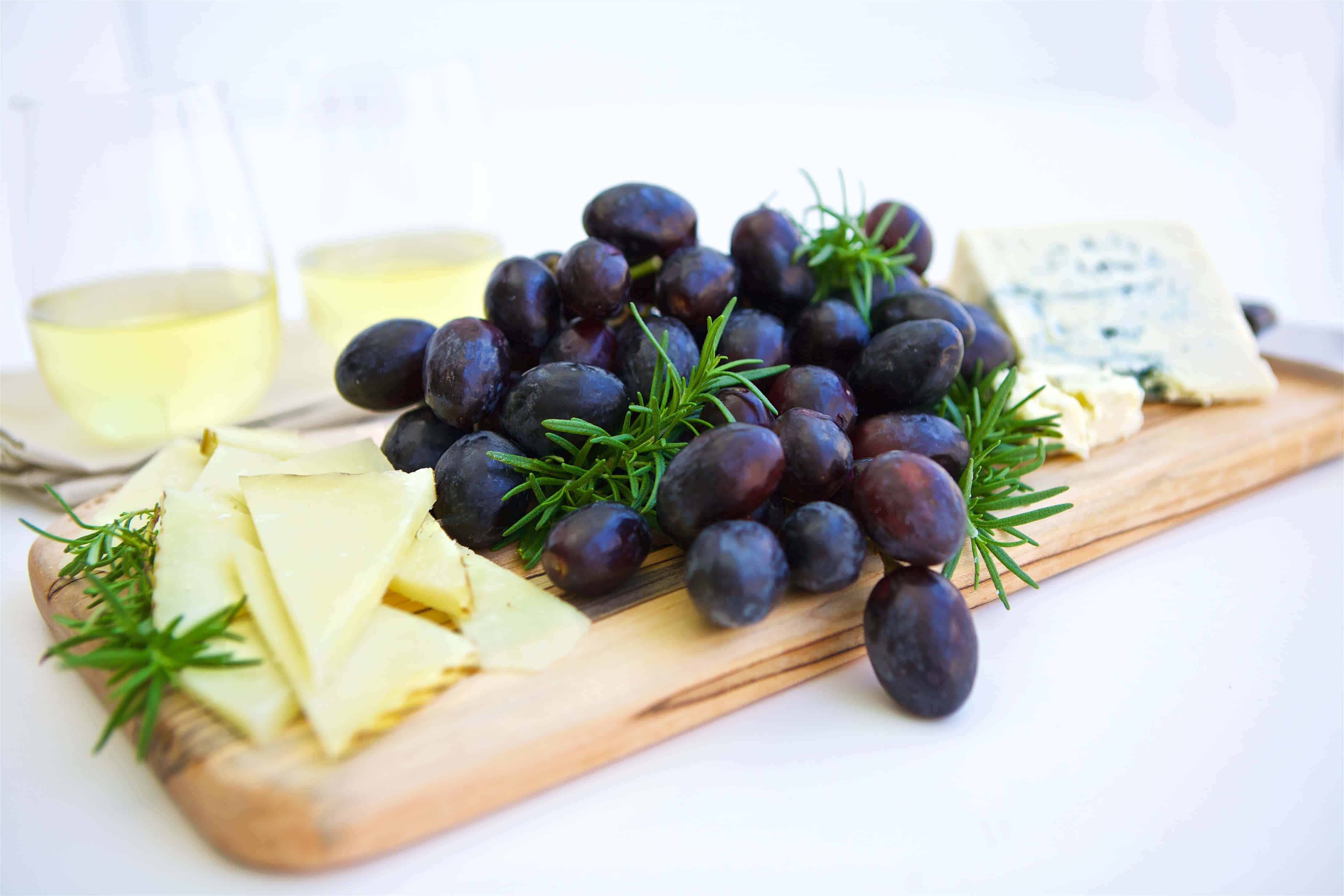 Black grapes paired with blue cheese on a board with garnish