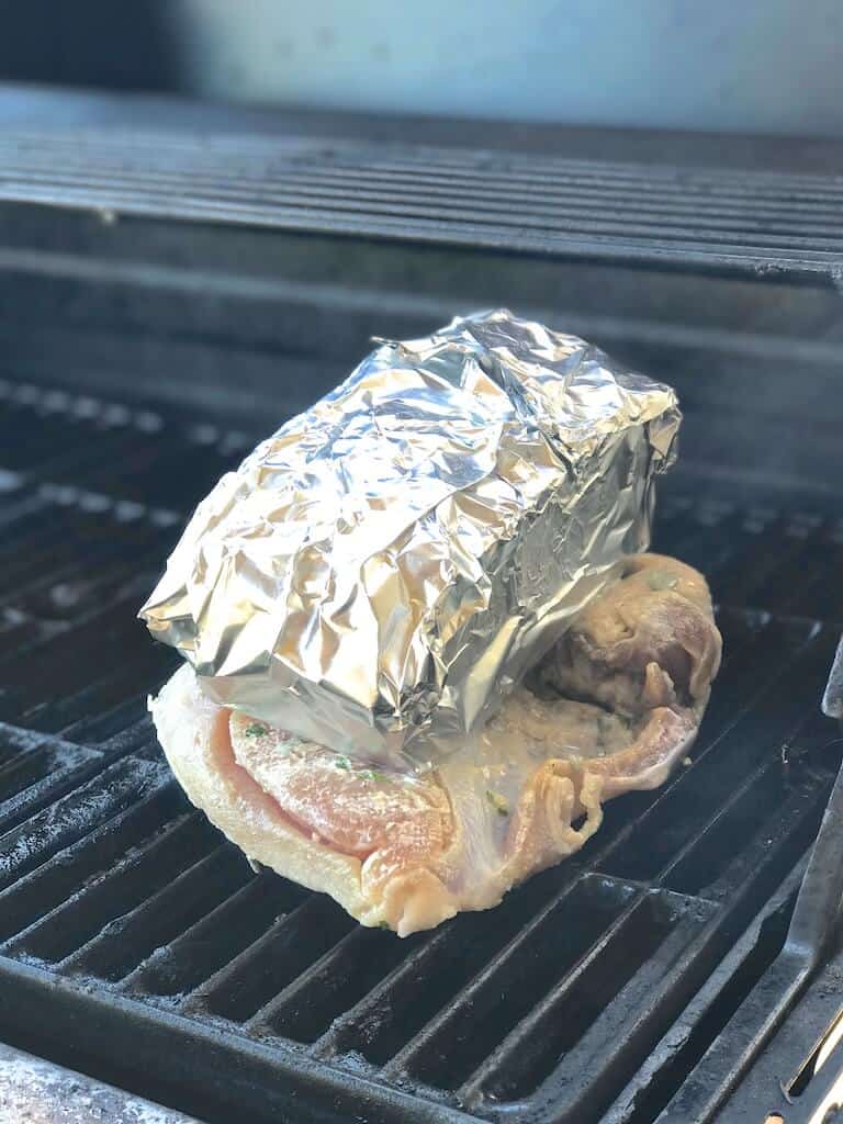 turkey on the grill with a foil-wrapped brick on top