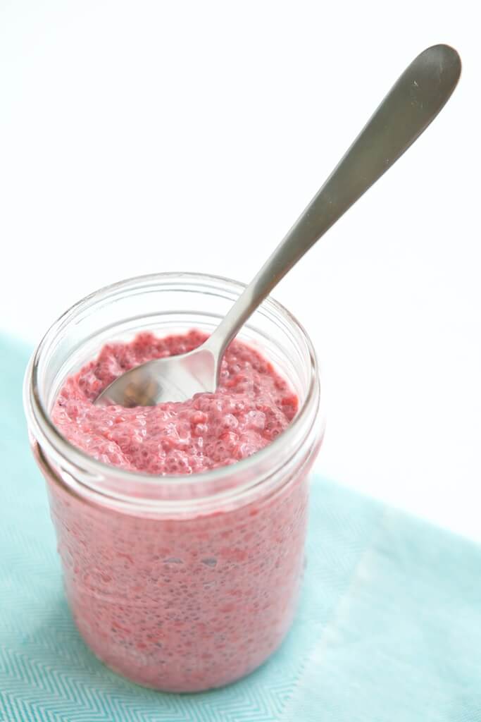 jar of raspberry chia pudding with a spoon