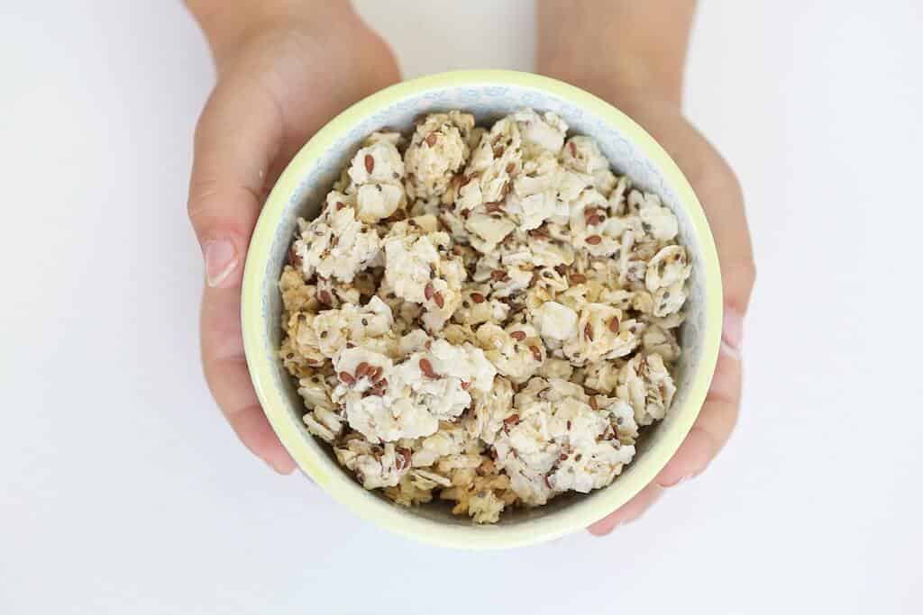 Two hands holding a bowl of Growing Roots snack clusters