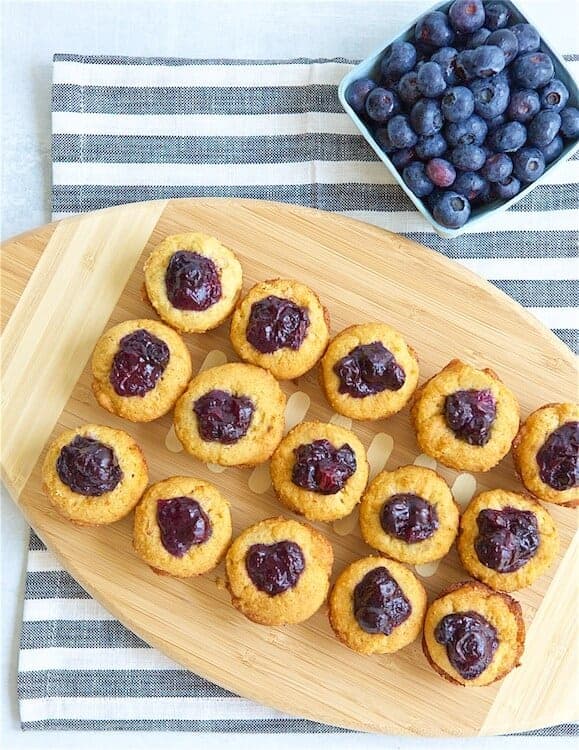 Boozy Blueberry Bacon Bites next to a bowl of blueberries