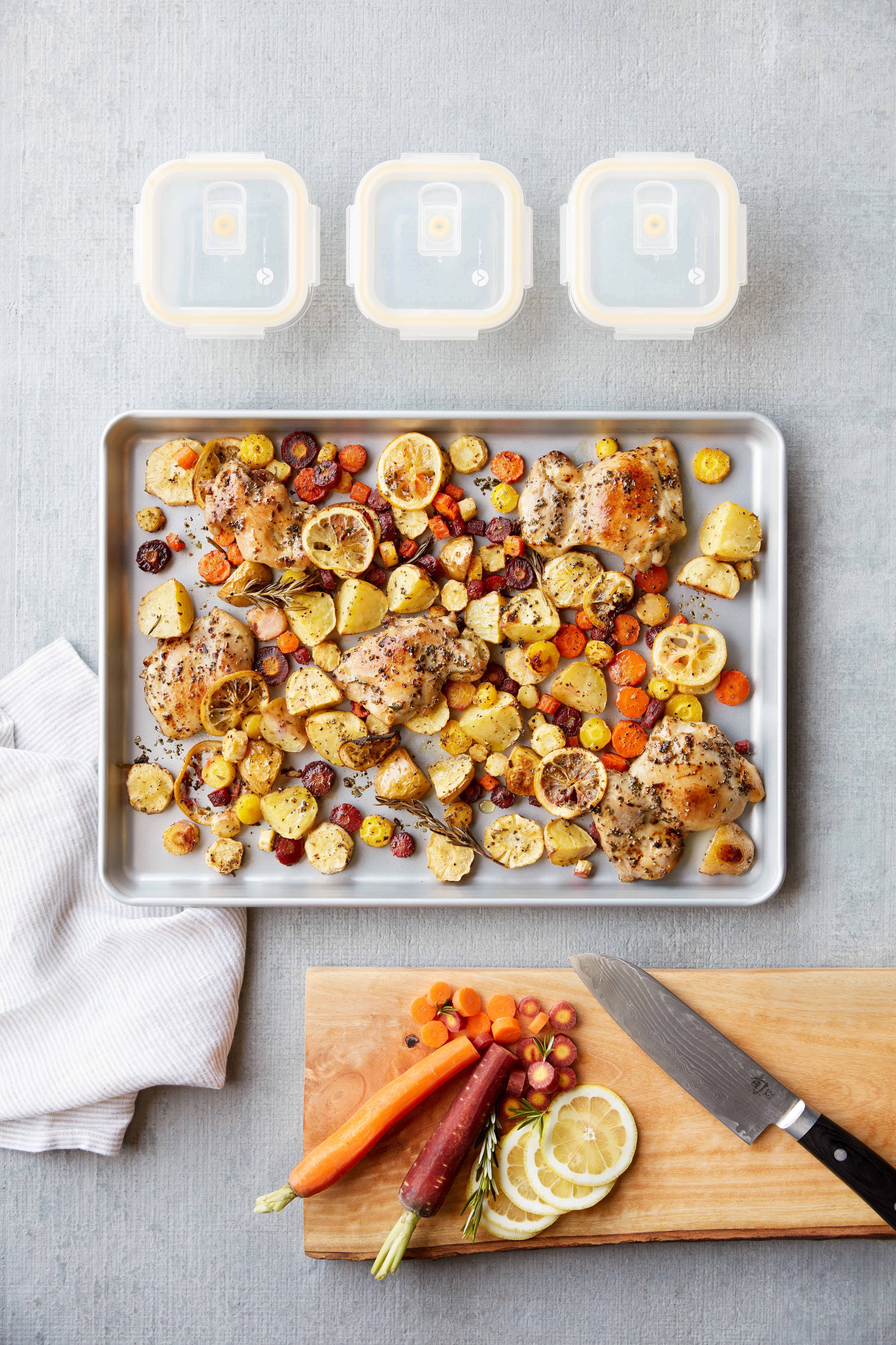 Sheet Pan Lemon Chicken next to a cutting board of vegetables and lemons