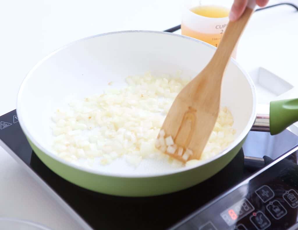 Using a wooden spatula to saute the onions.