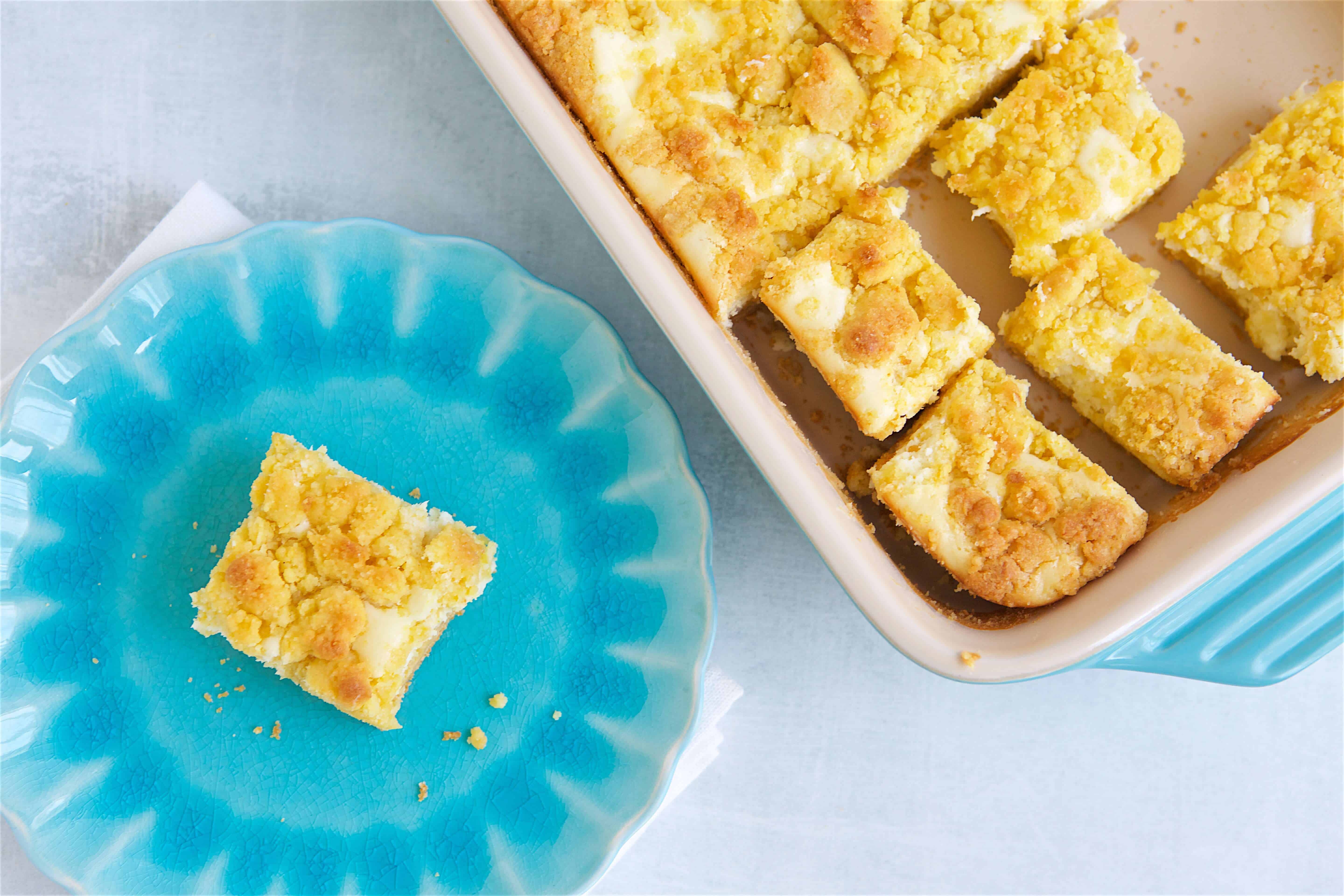 sliced lemon bars in a dish and one on a blue plate.