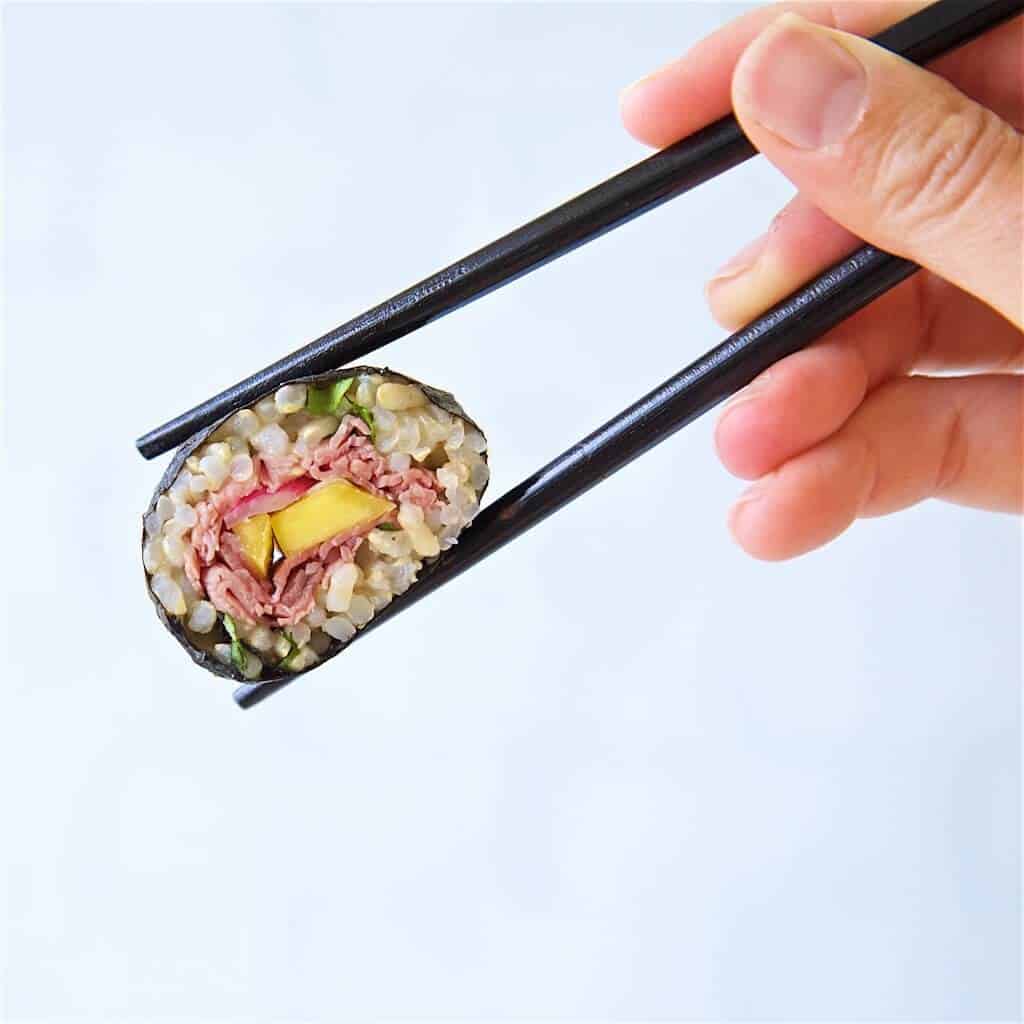 Sushi roll being held by chopsticks