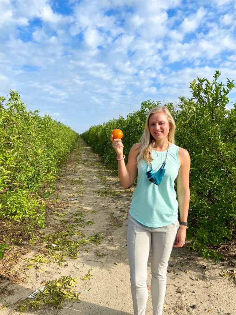 Jenna Standing in a citrus grove holding a tangerine