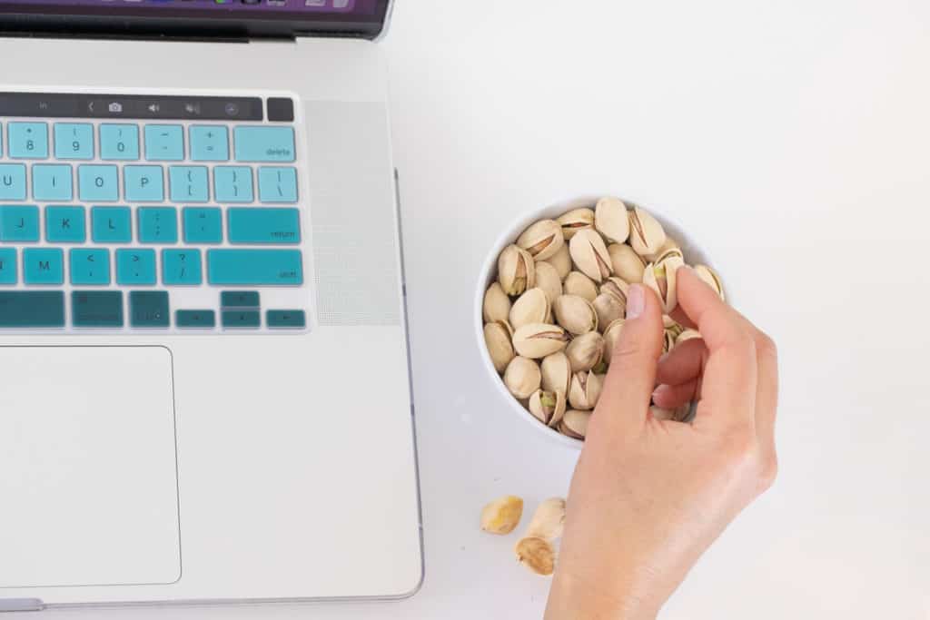 Picking up a pistachio from a bowl