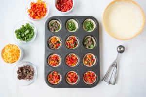 Filling muffin tins with veggies - Sausage mini breakfast pies