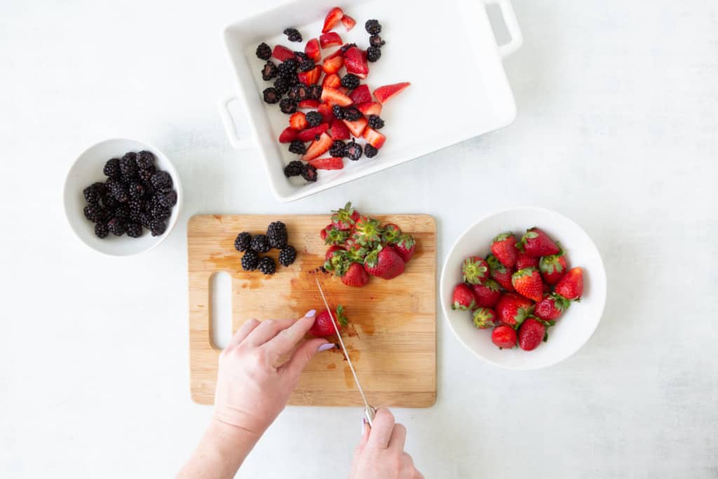 Cutting berries in half then placing in a 1 quart baking dish