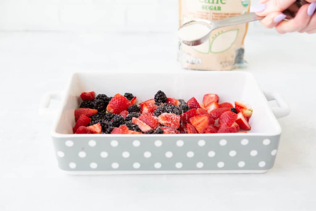 Adding sugar to the sliced berries