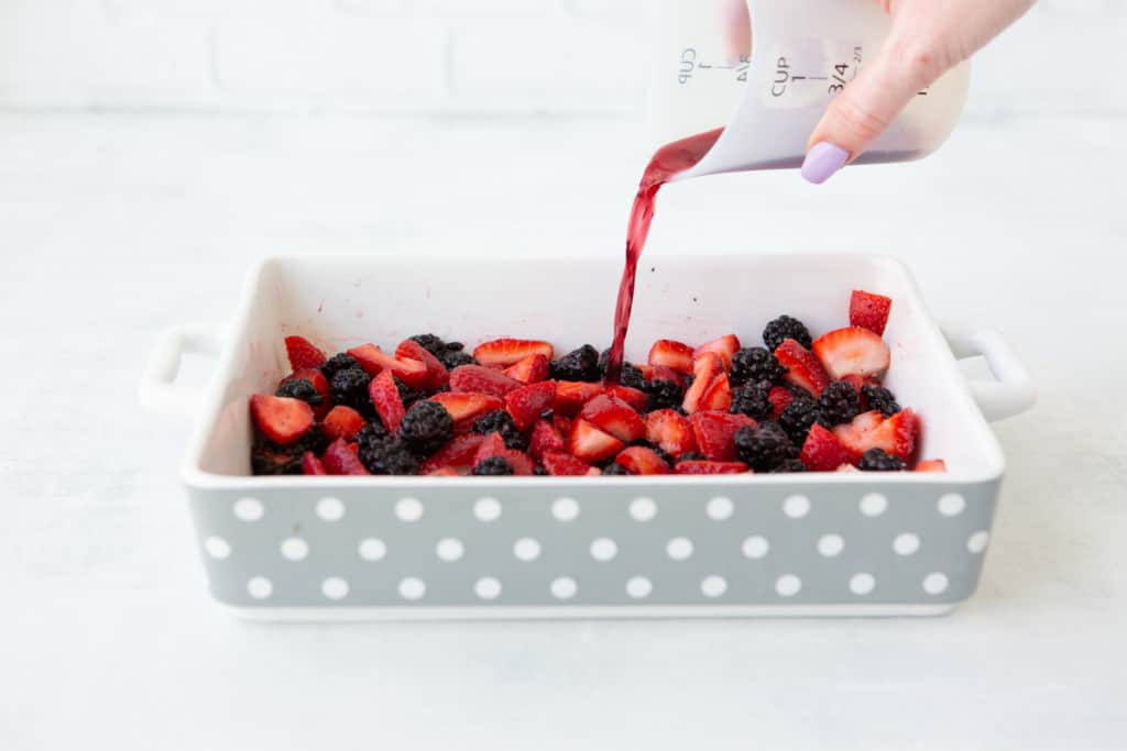 Cabernet berry compote - pouring cabernet wine over berries in baking dish