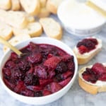 Cabernet berry compote in bowl shown on top of crostini with mascarpone cheese