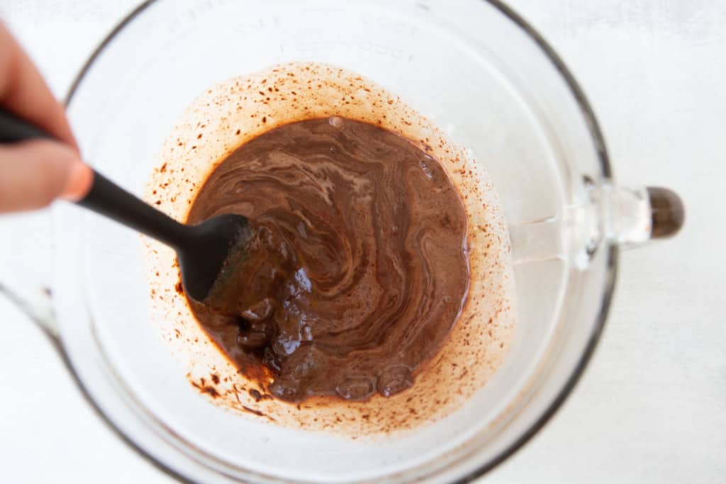 Mixing chocolate and hot cream in a bowl to make chocolate ganache