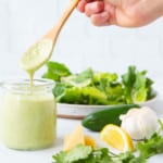 Jalapeno Cilantro Caesar dressing in a jar about to be poured on to salad.