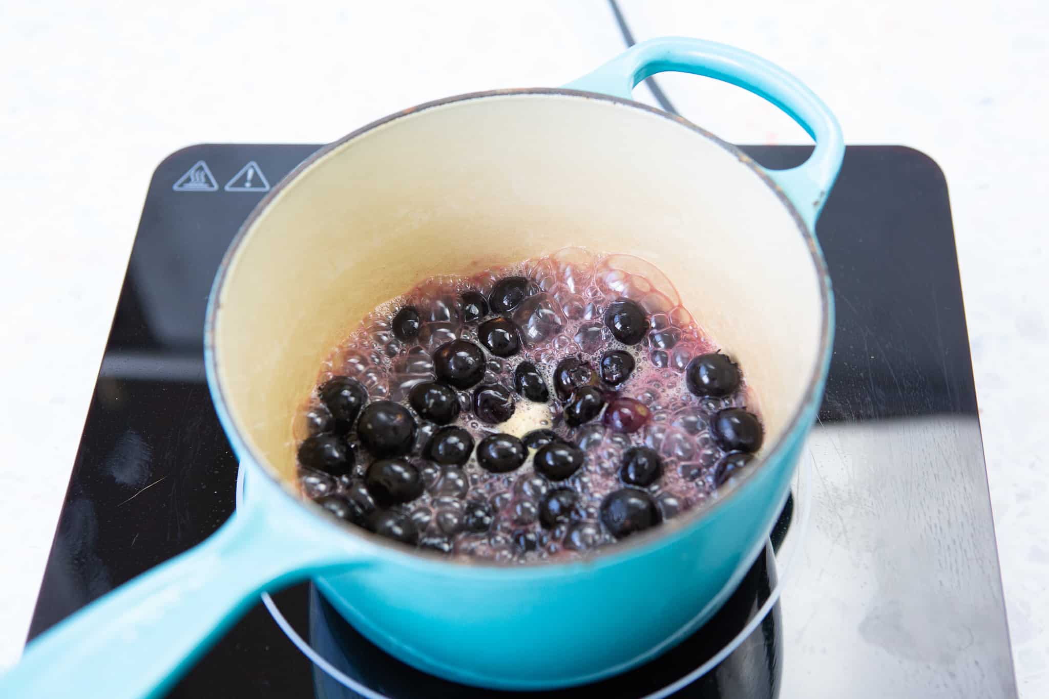 blueberries and orange juice simmering in a small sauce pot
