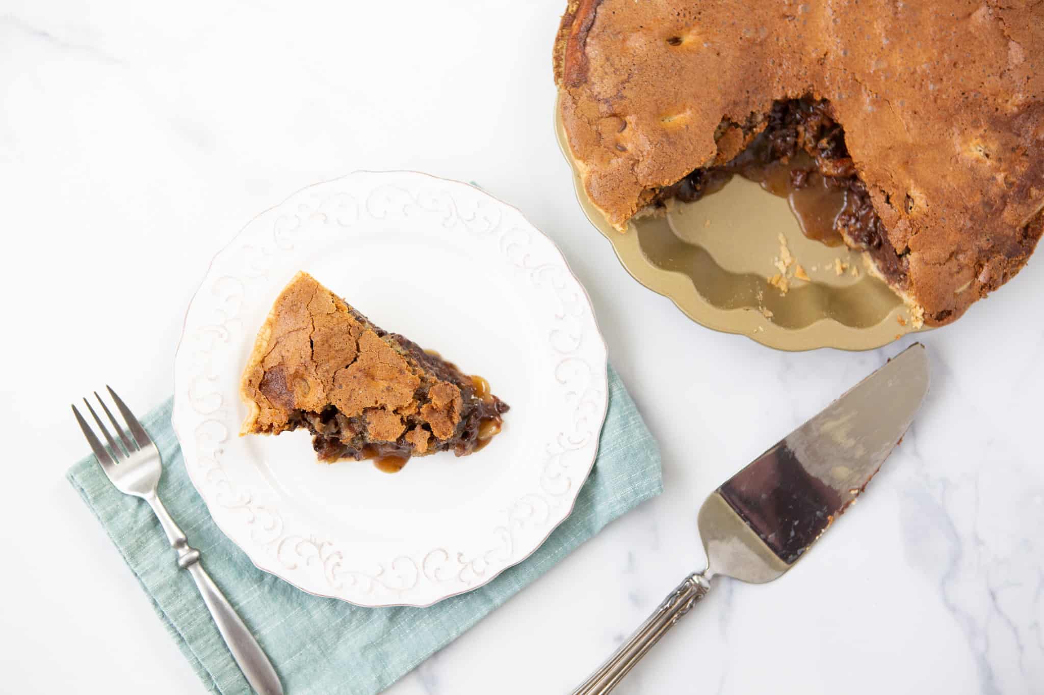 slice of chocolate chip pecan pie on a plate next to the whole pie