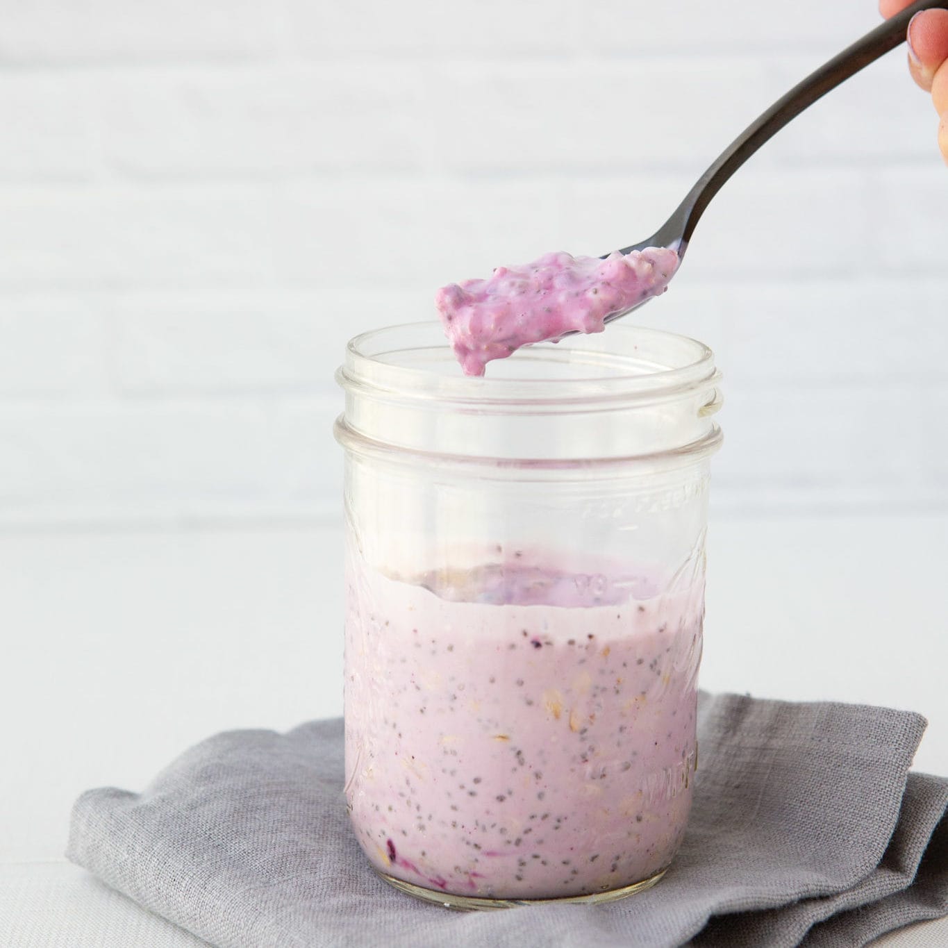 blueberry vanilla overnight oats in a mason jar with spoon showing the texture of this easy breakfast.