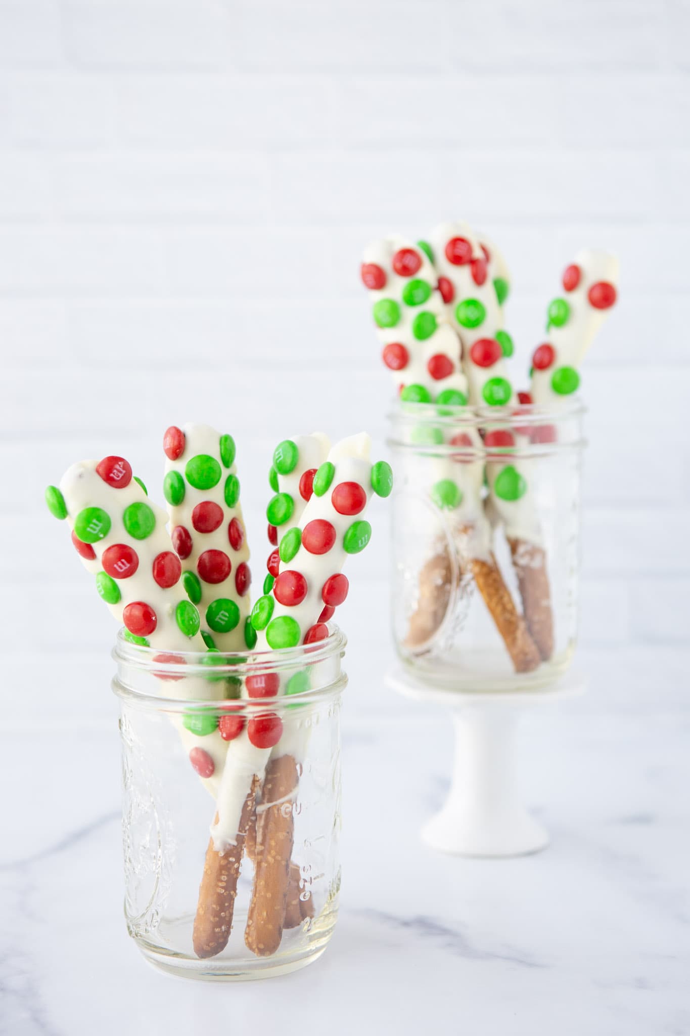 white chocolate dipped pretzel rods with holiday m&ms in mason jars