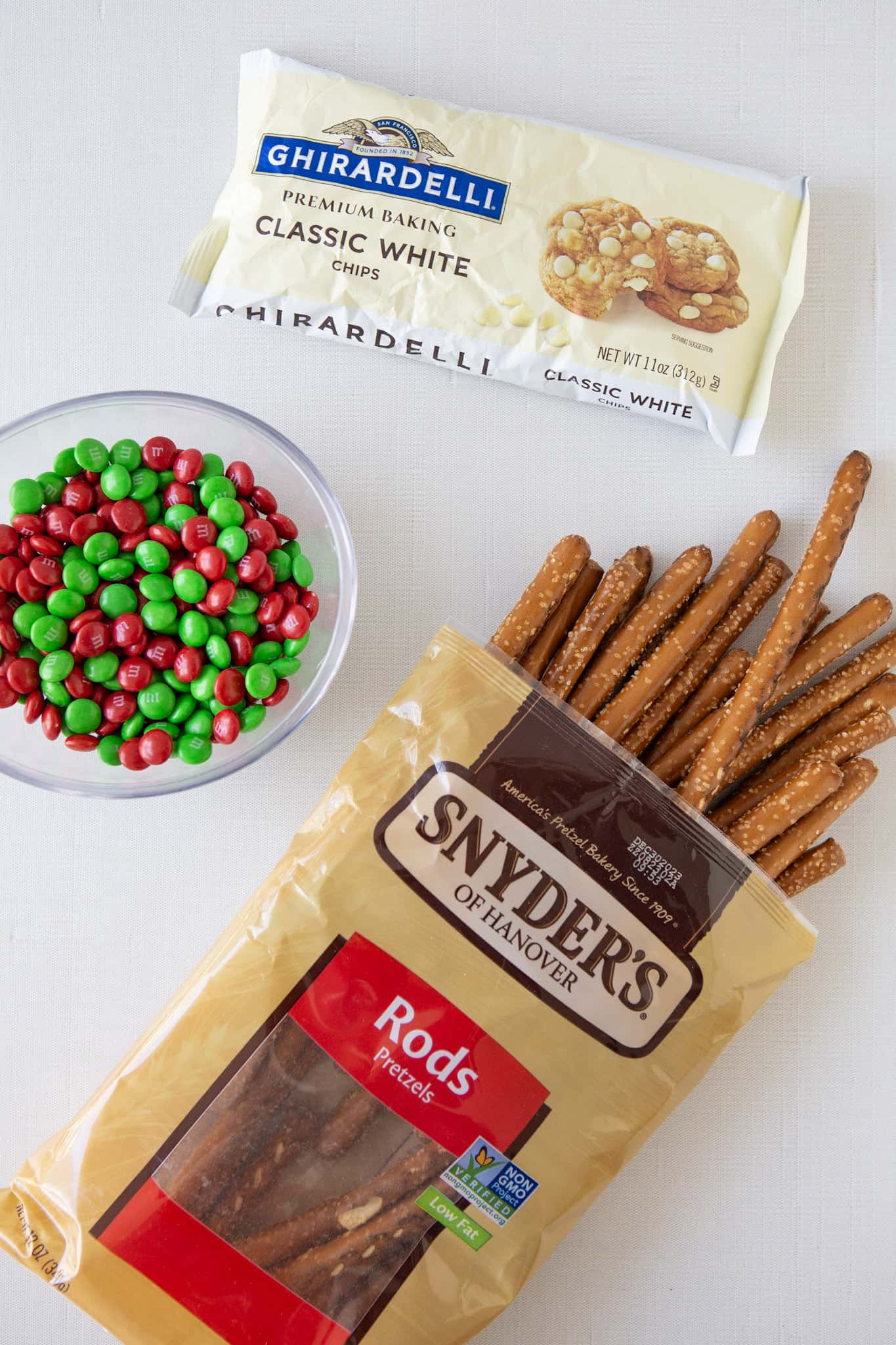 overhead shot of ingredients for white chocolate dipped pretzel rods with m&ms 