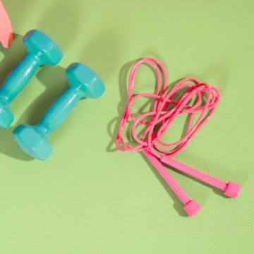 jump rope HIIT workout, jump rope on exercise mat next to two dumbbells