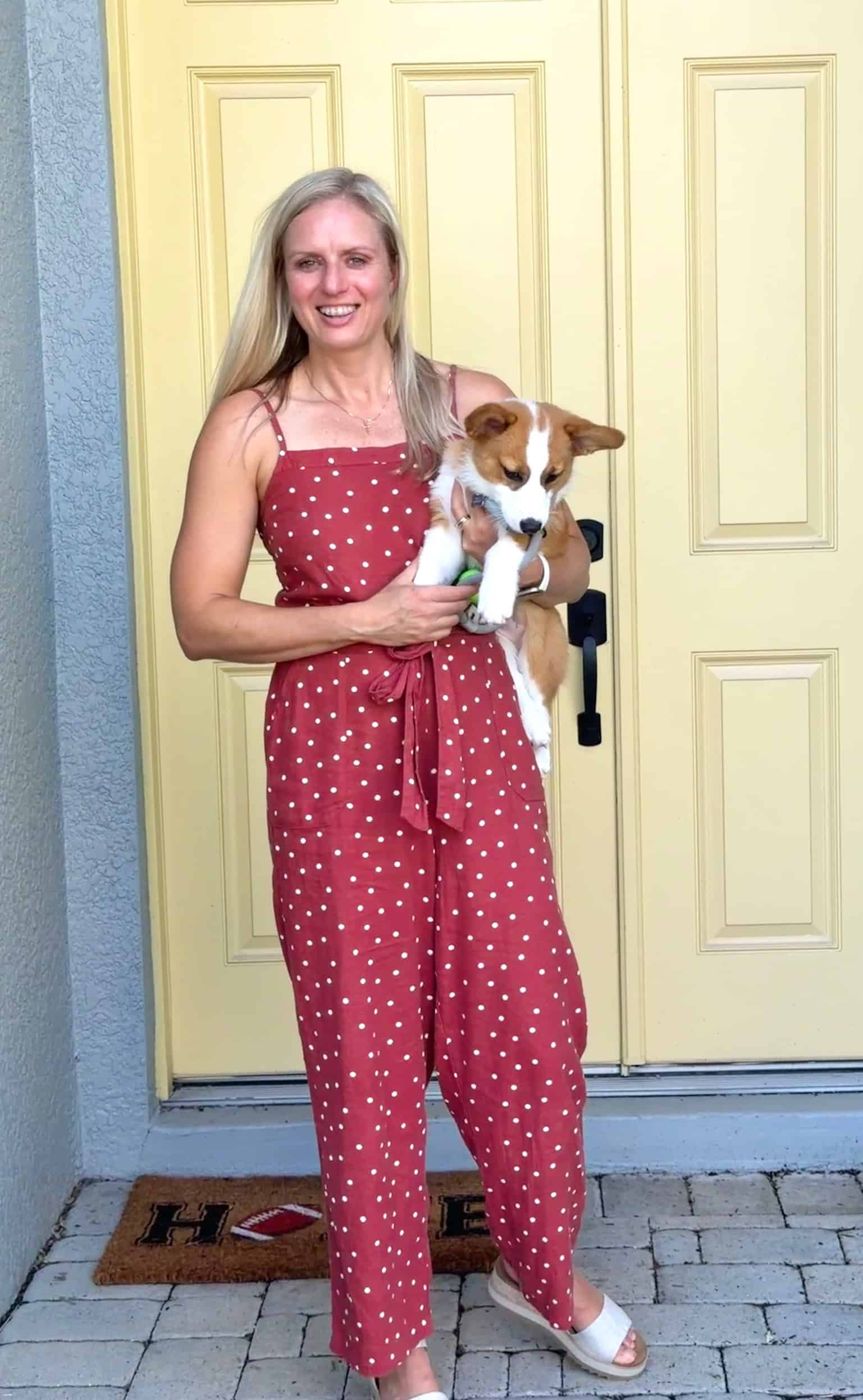 Jenna wearing a red with white polka dots jumpsuit from Stitch Fix holding her dog